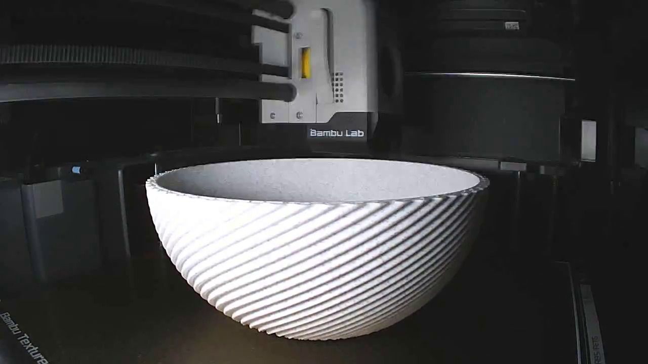 Een geribbelde witte schaal op het printbed van een Bambu Lab-printer