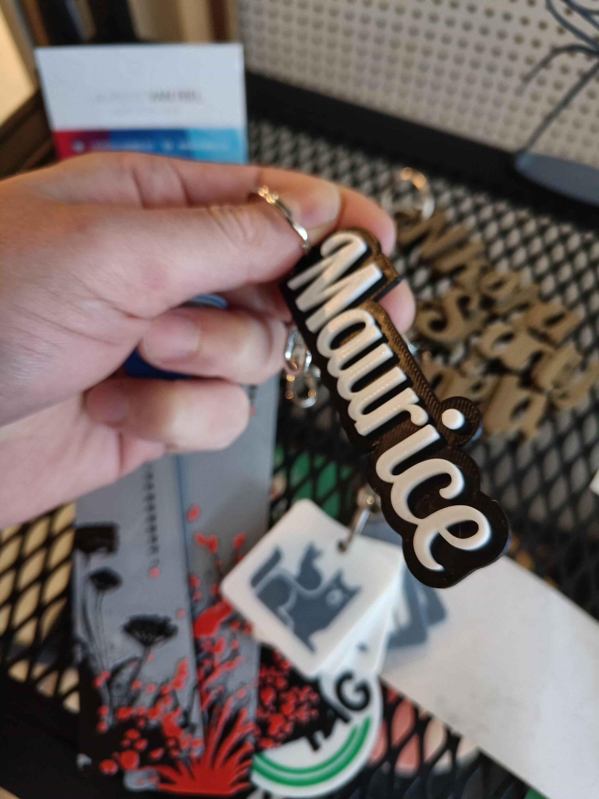 Een hand met een sleutelhanger waarop Maurice staat in verhoogde witte letters op een zwarte basis
