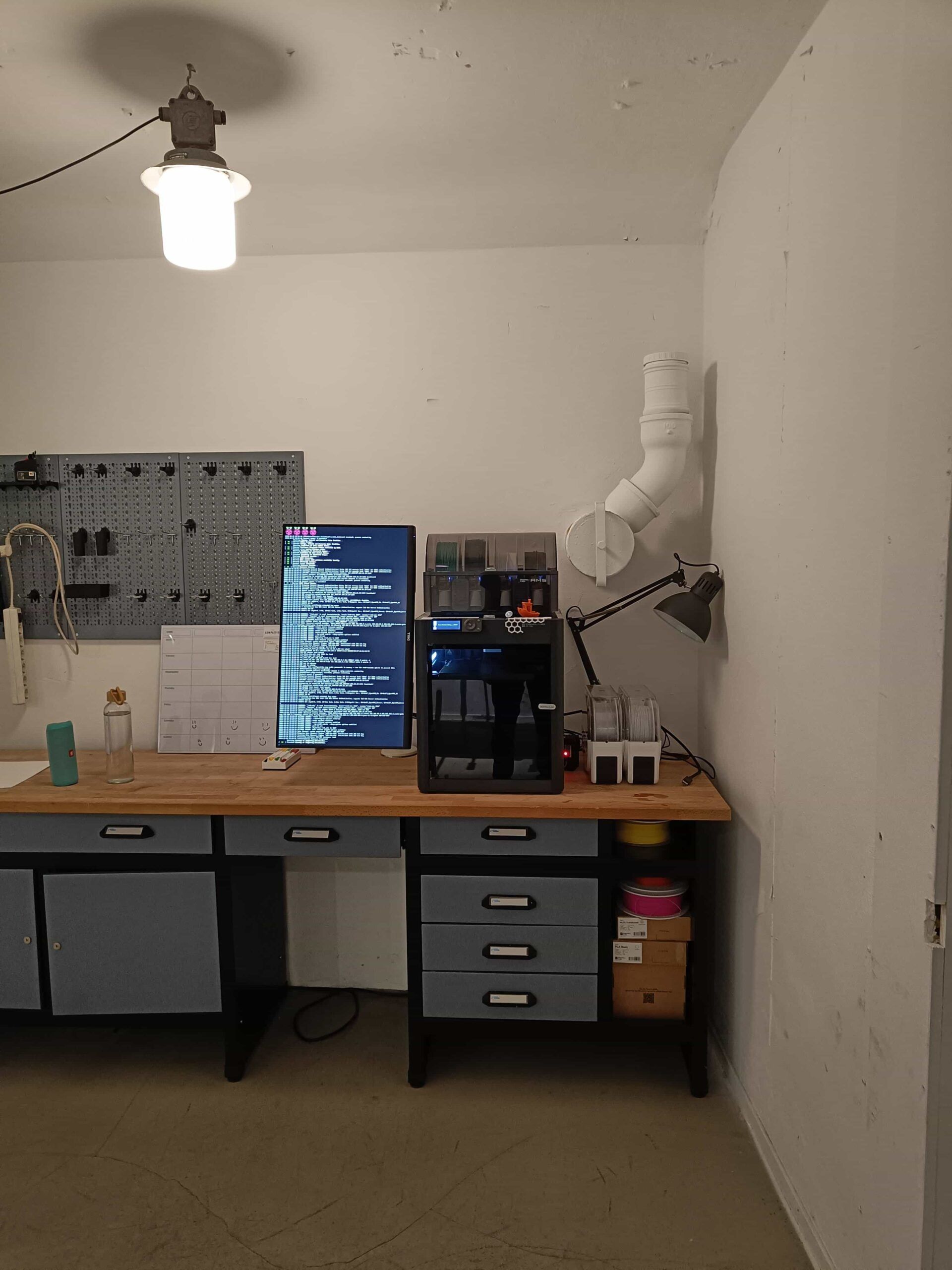 Een Bambu Lab-printer met spoelen filament ernaast op een houten werkbank